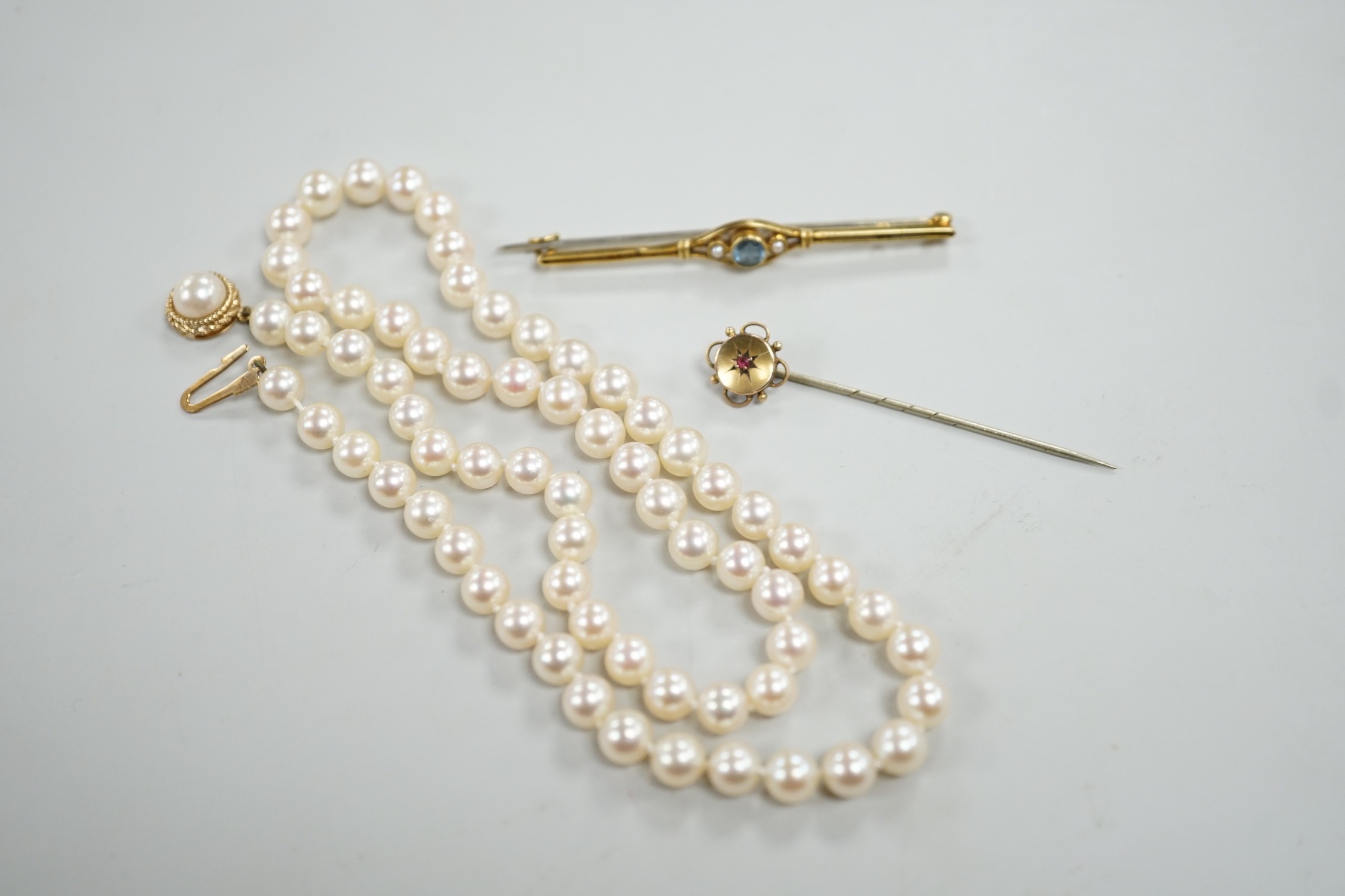 A single strand cultured pearl necklace, with 9ct gold clasp, 46cm, together with a yellow metal and ruby stick pin and a similar gem set bar brooch.